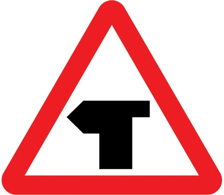 A white triangle with a red border and a black T shape